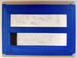 Photograph of two horizontal rectangular strips taped onto a surface with blue painter's tape forming a border around them. The top strip is mostly white with faint gray smudges, while the bottom strip has a similar white area above a solid black section at the left.