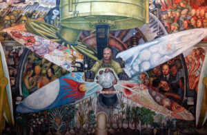 A mural depicting a central figure operating a large mechanical device with four colorful, intricately designed blades extending outward, each blade featuring distinct symbolic imagery representing science, technology, agriculture, and human progress. Surrounding the central scene are groups of people and machinery, highlighting themes of industrialization, innovation, and societal development through vibrant colors and detailed composition.