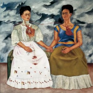 Painting depicting two women sitting side by side, connected by a red artery linking their exposed hearts, symbolizing emotional and physical connection. One woman wears a white dress with lace and holds surgical scissors cutting the artery, while the other wears a blue and brown dress, both set against a stormy sky background.
