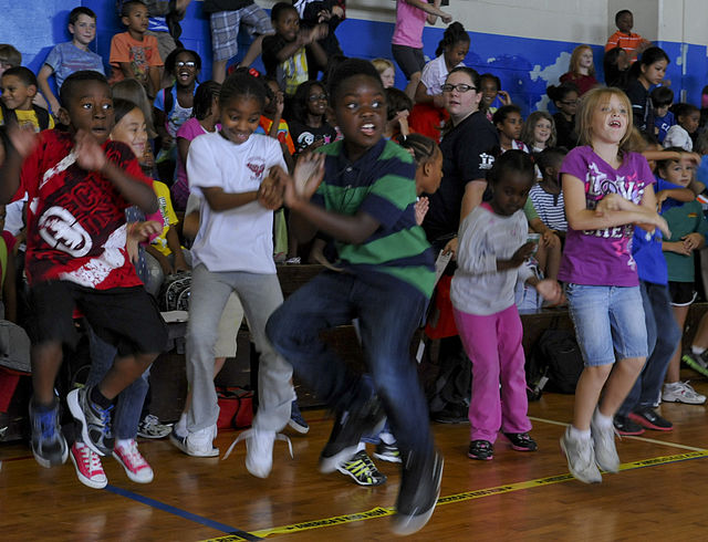 Children dancing in a school gym.