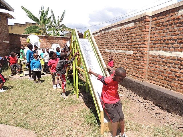 A large group of children playing on and around a wooden slide.