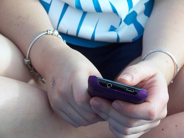 Close up of two hands holding a phone.