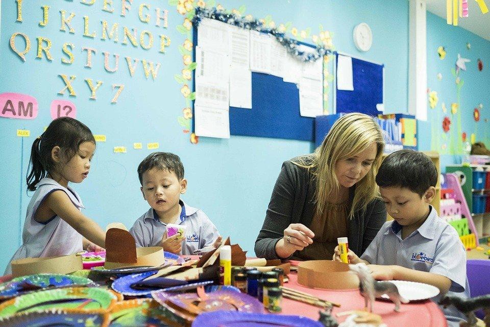 teacher sitting at a table working on art with three students