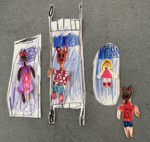 Hand-drawn paper cutouts of bears and a figure on a gray surface.