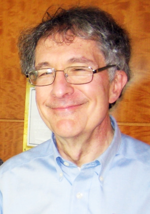 Middle aged man with gray hair and glasses smiling.