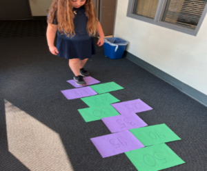 Child using colored papers, counting by 5s, to hopscotch