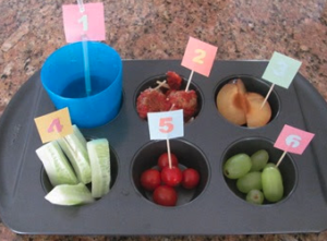 Muffin tin with fruit and numbers on toothpicks