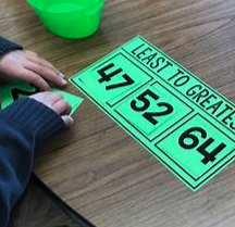 Child placing 2-digit numbers from least to greatest