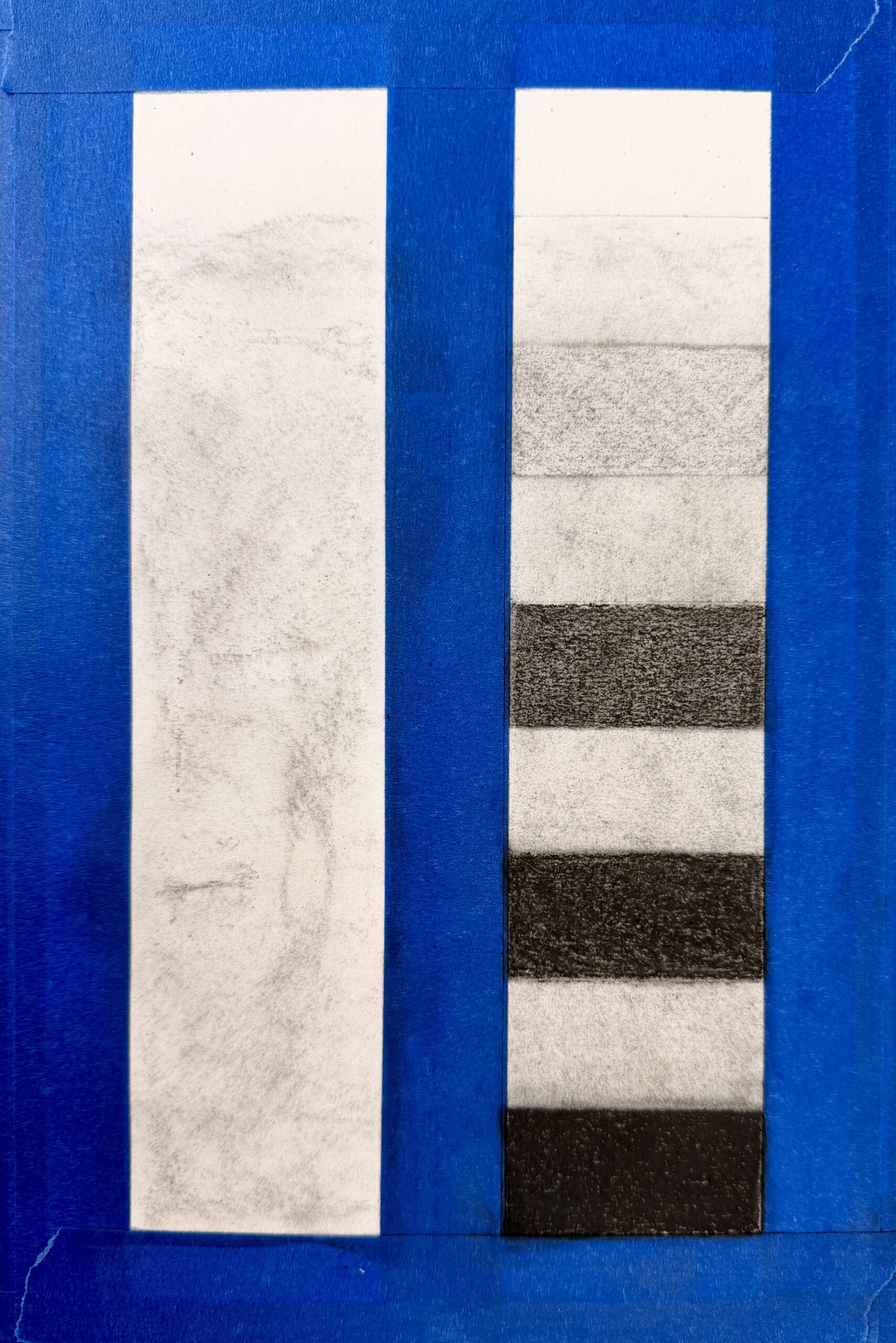 Photograph of two rectangular strips side by side on a blue background, with the top strip showing a faint, uneven gray texture and the bottom strip displaying six vertical black and white alternating bands. The contrast between the solid bands and the subtle shading suggests a comparison of shading techniques.