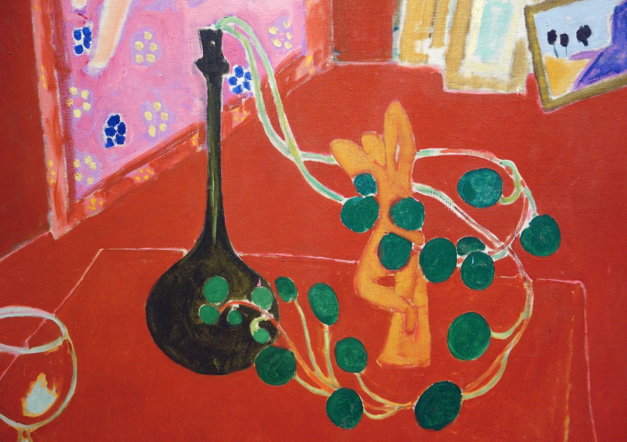 Painting of a still life scene featuring a dark bottle, an orange sculpture, and a trailing plant with green leaves on a red surface. Background includes a pink wall with blue floral patterns and framed artwork with abstract shapes.