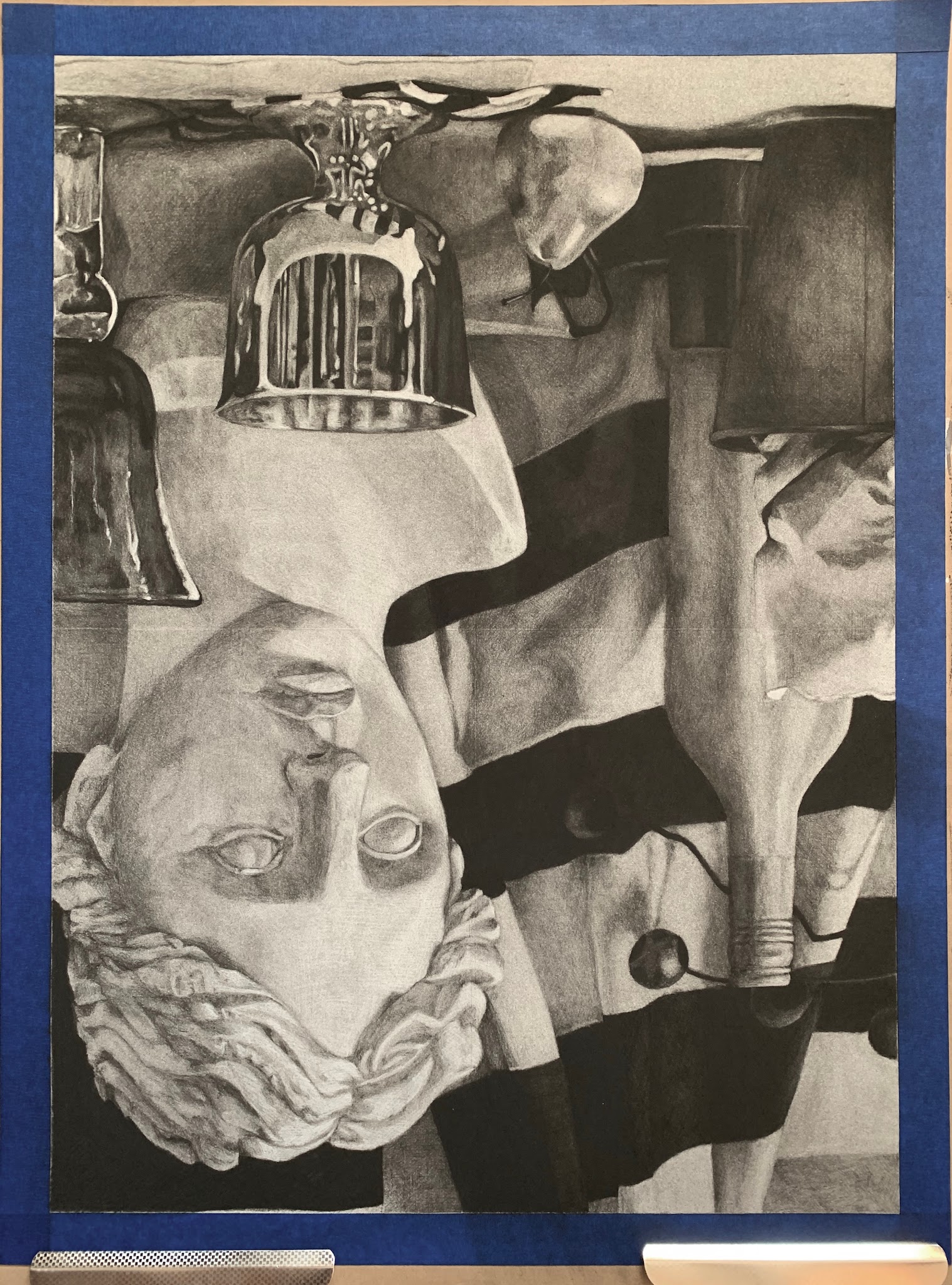 Drawing depicting a classical bust surrounded by various glass bottles and objects on a striped cloth background seen from upside down. The composition highlights detailed textures and contrasts between smooth surfaces of the bust and reflective qualities of the glass elements.