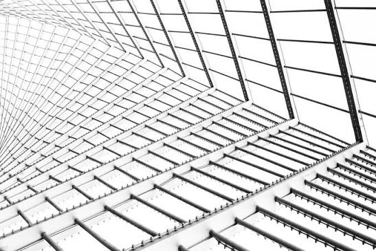 Photograph of an architectural structure featuring a repetitive pattern of angled beams and rectangular panels in black and white. The design creates a sense of depth and perspective with strong geometric lines and contrast.