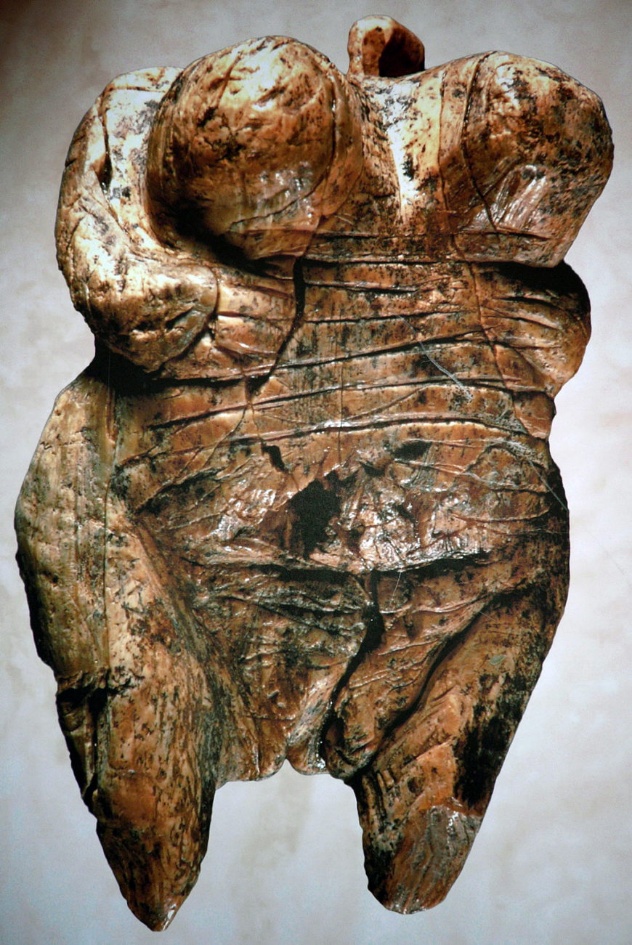 Female Figure of Hohlefels carved torso of a female figure featuring enlarged breasts and incised lines to indicate public region. Lines are marked horizontally across the body with arms tucked in and no head on the piece.