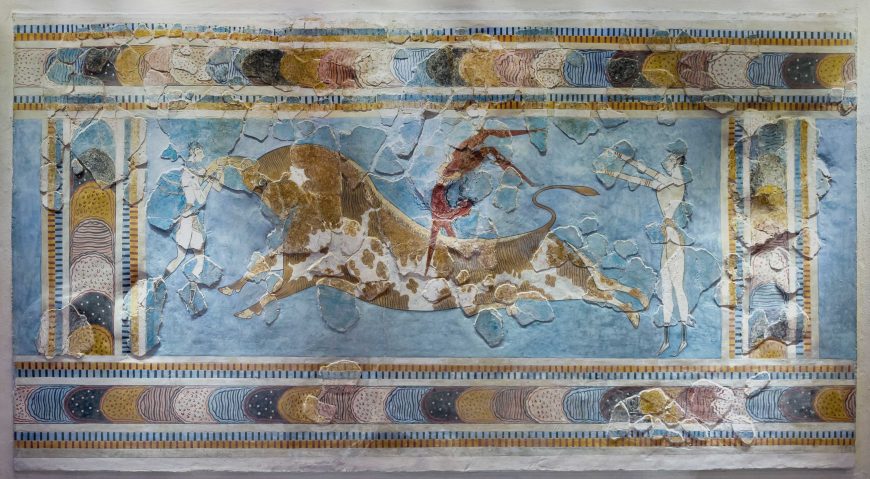 A fresco painting depicting a bull-leaping scene with a central figure vaulting over a large bull, flanked by two standing figures on either side. The artwork features a blue background with decorative borders containing circular patterns in earthy tones of brown, yellow, and white.