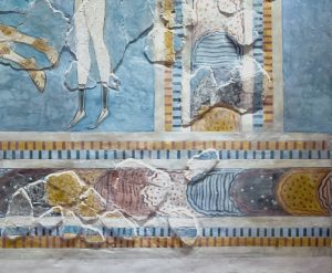 Bull-leaping fresco (detail) close up of the border featuring muted colors like blue, yellow, and white. The artwork includes horizontal bands with geometric patterns and shows signs of wear and damage.