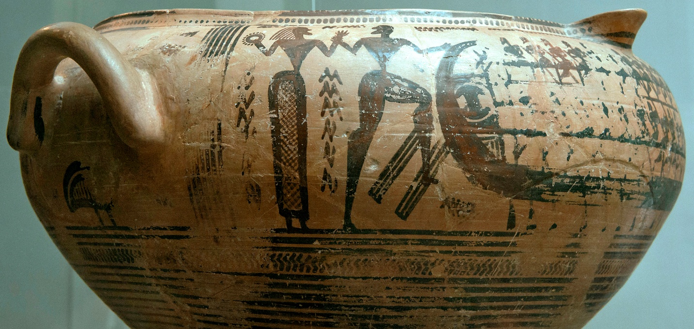 Photograph of an ancient Greek terracotta vessel featuring black-figure decoration depicting human figures and geometric patterns. The vessel has a rounded body with a handle, showcasing detailed silhouettes of standing and seated figures, along with ornamental motifs arranged in horizontal bands.