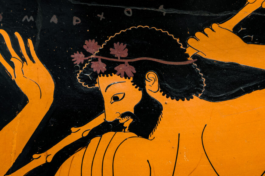Detail, Euthymides, Three Revelers Greek vase painting depicting a bearded man with curly hair wearing a floral crown, holding a staff. The artwork features black and orange colors with detailed facial expressions and intricate line work highlighting the figure's muscles and hair.