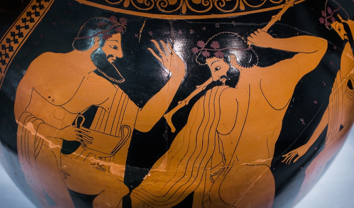 Drinking and dancing with kantharos (detail), Euthymides, Three Revelers red-figure pottery vase depicting two bearded men, one playing a lyre and the other holding a staff. The scene features detailed line work, floral headbands, and traditional Greek attire, highlighting cultural and artistic elements.