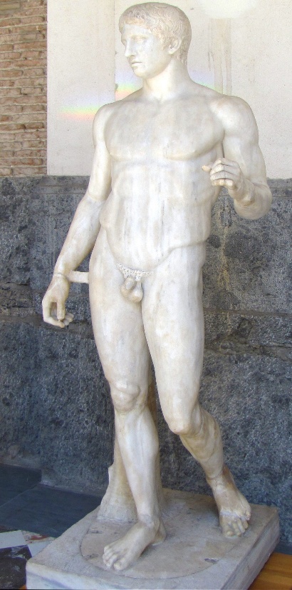 Polykleitos, Doryphoros (Spear-Bearer) nude youthful male sculpture carved from marble without paint on its current surface. The figure stands in contrapposto stance with his left arm lifted and bent at a 90 degree angle.