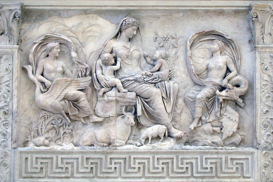 Bas-relief sculpture depicting a central seated female figure with two children, flanked by two winged figures, one on each side. The scene includes detailed elements such as animals, plants, and a geometric border pattern at the bottom, showcasing classical artistic style and mythological themes.