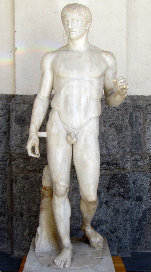 Polykleitos, Doryphoros (Spear-Bearer) nude youthful male sculpture carved from marble without paint on its current surface. The figure stands in contrapposto stance with his left arm lifted and bent at a 90 degree angle.