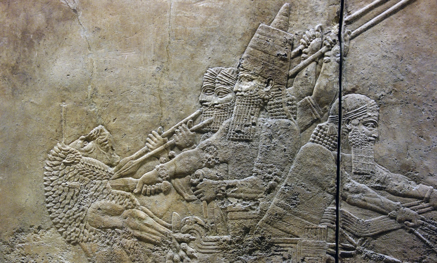 Ashurbanipal slitting the throat of a lion from his chariot (detail), Ashurbanipal Hunting Lions stone relief depicting Assyrian warriors in battle, featuring detailed carvings of figures with helmets, weapons, and armor. The relief highlights intricate textures of hair, beards, and clothing, emphasizing a dynamic scene of combat and historical military attire.