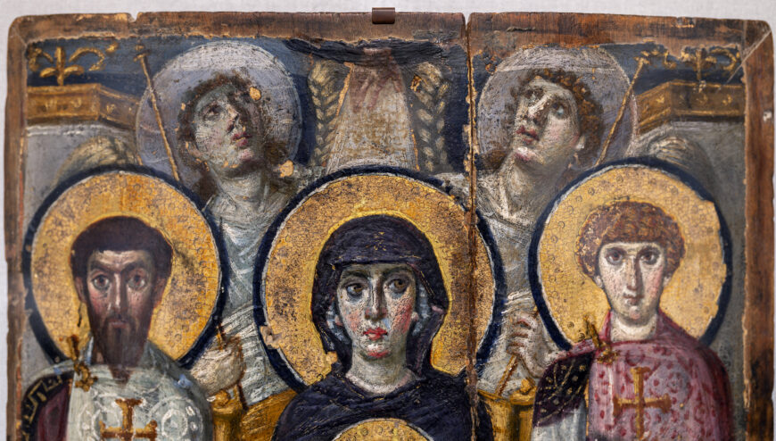 Detail image of a religious icon panel featuring five haloed figures with blurred faces, set against a richly decorated background with gold and blue tones. The panel shows intricate details such as crosses on garments and ornamental patterns.