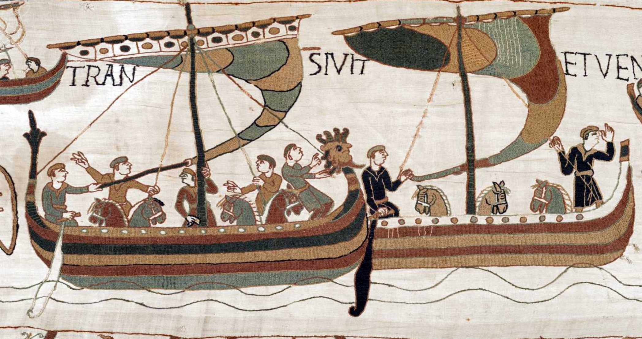 Tapestry embroidery depicting medieval ships with sailors engaged in various activities, showcasing detailed sails, rigging, and animal heads on the vessels' prows. The scene highlights maritime travel and naval elements from the historical period, with muted earth tones and stylized human figures.