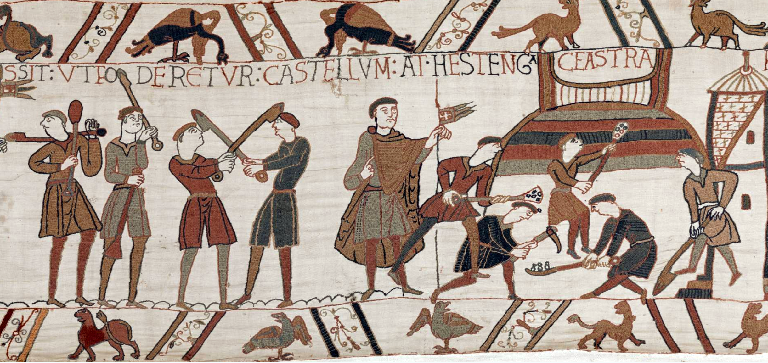 A medieval embroidered tapestry panel depicting a group of armed men preparing for war with some figures wielding weapons and others operating siege equipment. The scene includes Latin text labels and various animals, with a color palette dominated by earthy tones such as brown, beige, and dark red.