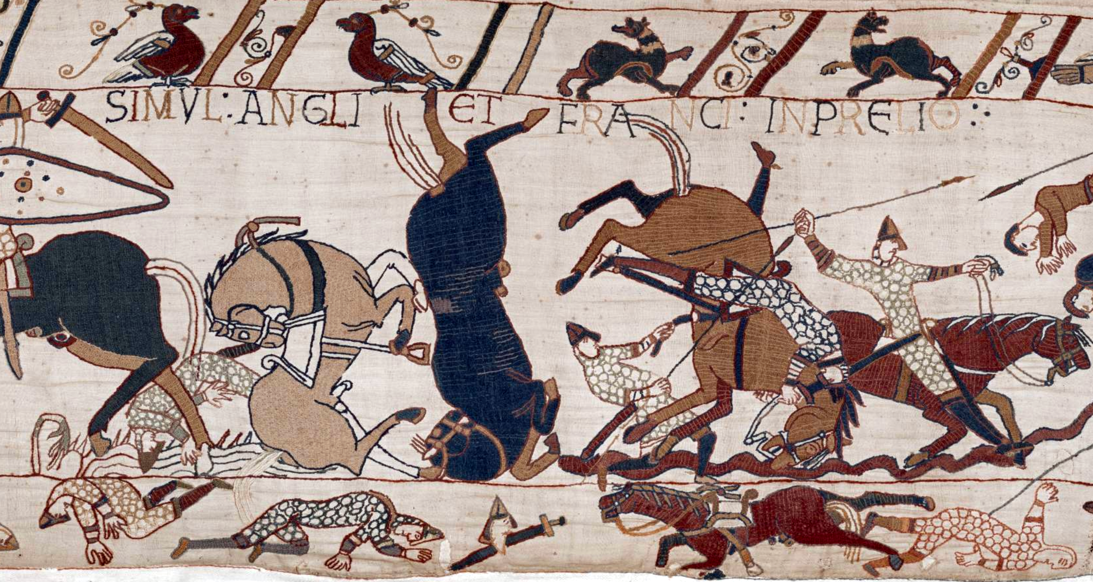 A detailed section of the Bayeux Tapestry depicting a chaotic battle scene with armored knights on horseback engaged in combat, some horses rearing or falling. The scene features Latin text above, intricate patterns on armor, and various animals, highlighting medieval warfare and artistic embroidery techniques.