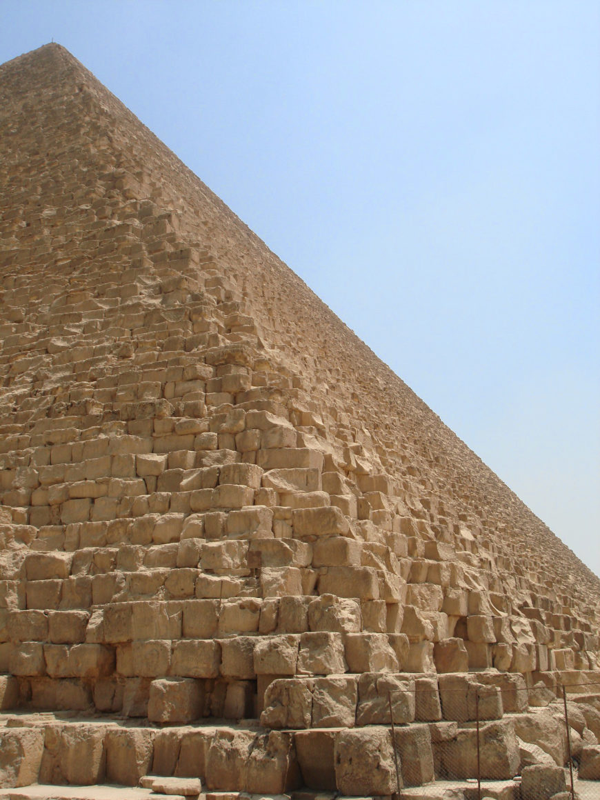 Photograph of a large ancient pyramid showing detailed core stone blocks forming its sloping side against a clear sky.