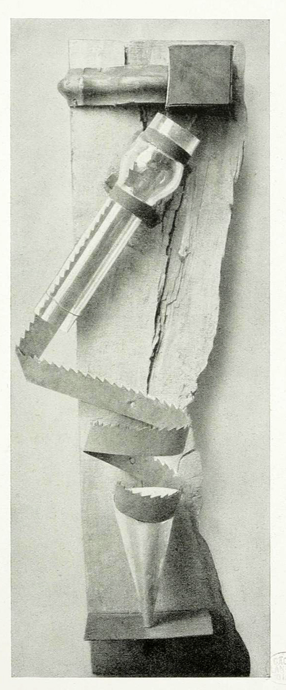 Black and white photograph of a mechanical device mounted on a wooden board, featuring a serrated metal strip coiled in a spiral shape. The device includes a cylindrical component with a glass section and a square box at the top.