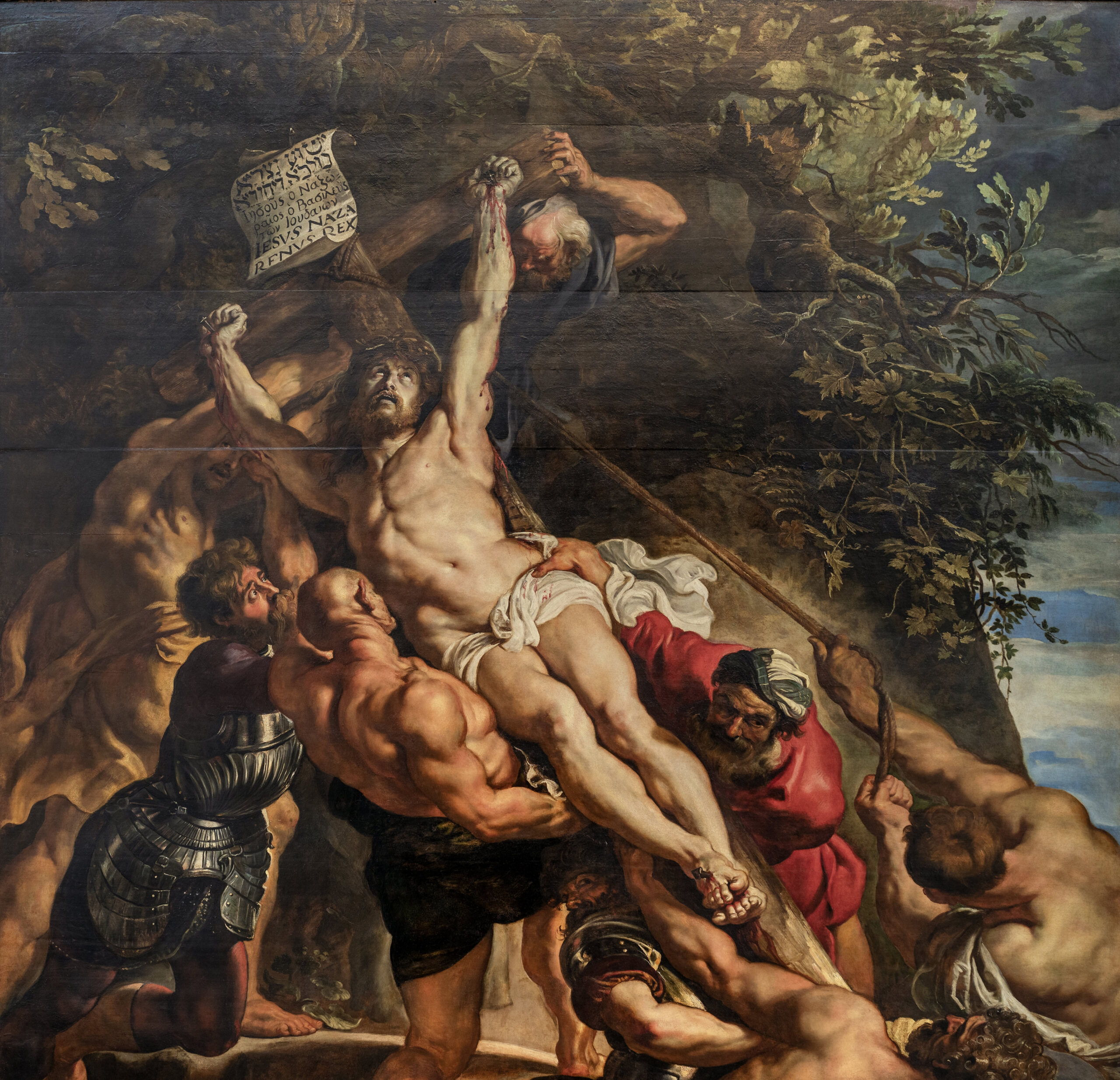 Peter Paul Rubens, Elevation of the Cross, with Christ crucified on the cross being elevated by several muscular men. The scene features dramatic lighting, intense expressions, and rich earthy tones, with a scroll bearing Latin text at the top of the cross.