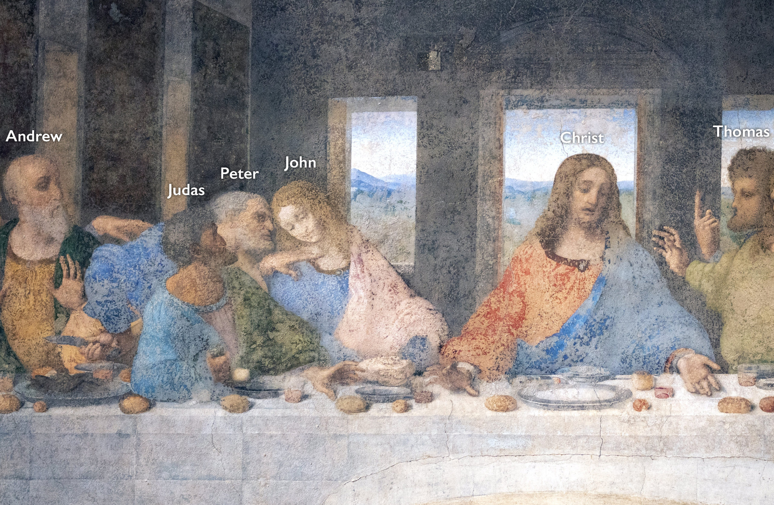 Detail of da Vinci's Last Supper fresco depicting a group of men seated at a long table, identified by labels as Andrew, Judas, Peter, John, Christ, and Thomas. The scene captures a significant biblical moment with detailed expressions, varied postures, and a background featuring windows showing a landscape.