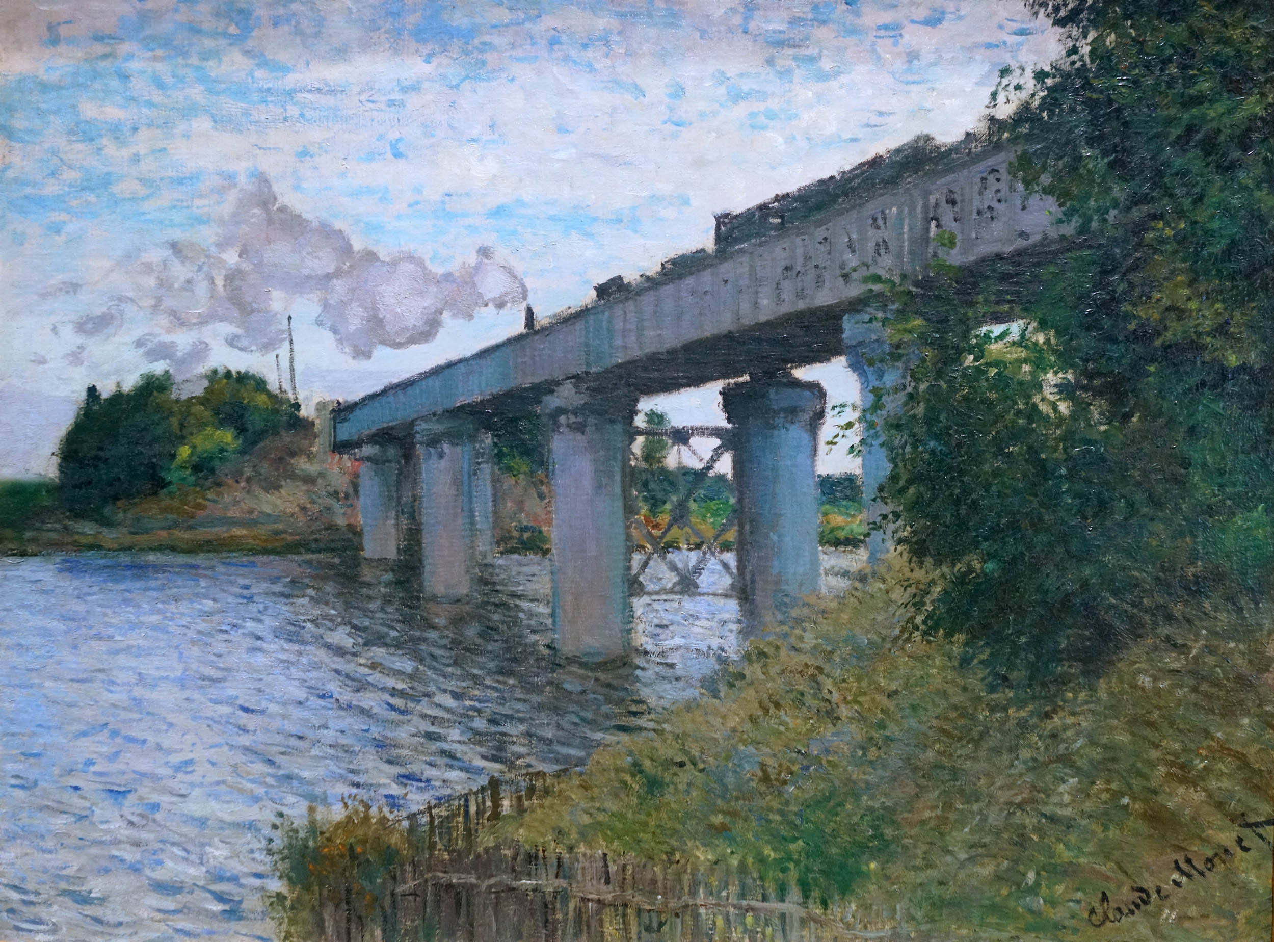Monet, The Railroad Bridge in Argenteuil painting of a train crossing a bridge over a river, showcasing impressionist brushwork and a natural landscape. Features smoke from the train, reflections in water, and lush greenery framing the scene.