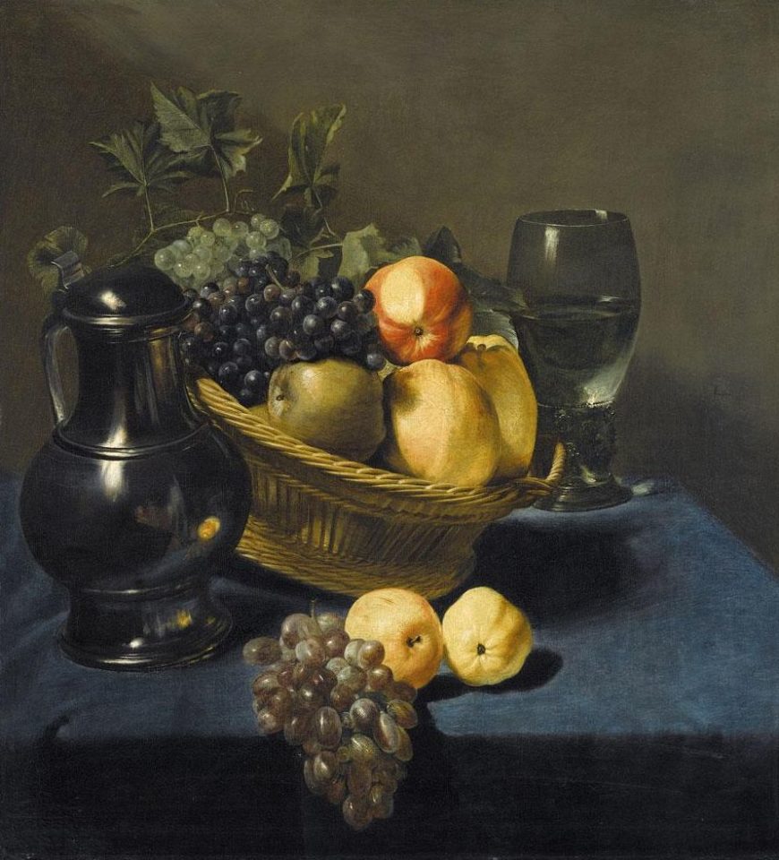 Still life painting depicting a woven basket filled with grapes, pears, and a peach, accompanied by a black pitcher and a glass of water on a dark blue cloth. The composition highlights rich textures and natural colors, emphasizing contrast between shiny surfaces and soft fruit.