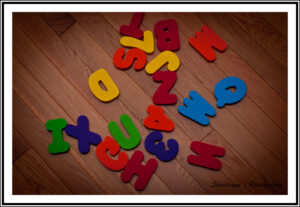 Colorful children's wood letters are scattered on a wood floor.